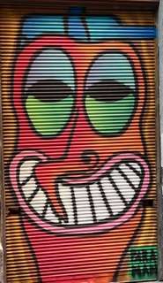 Irresistable smile on a goofy orange faced face and funny crooked nose street art